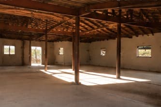 The empty shell with timber columns and roof beams, light on the floor