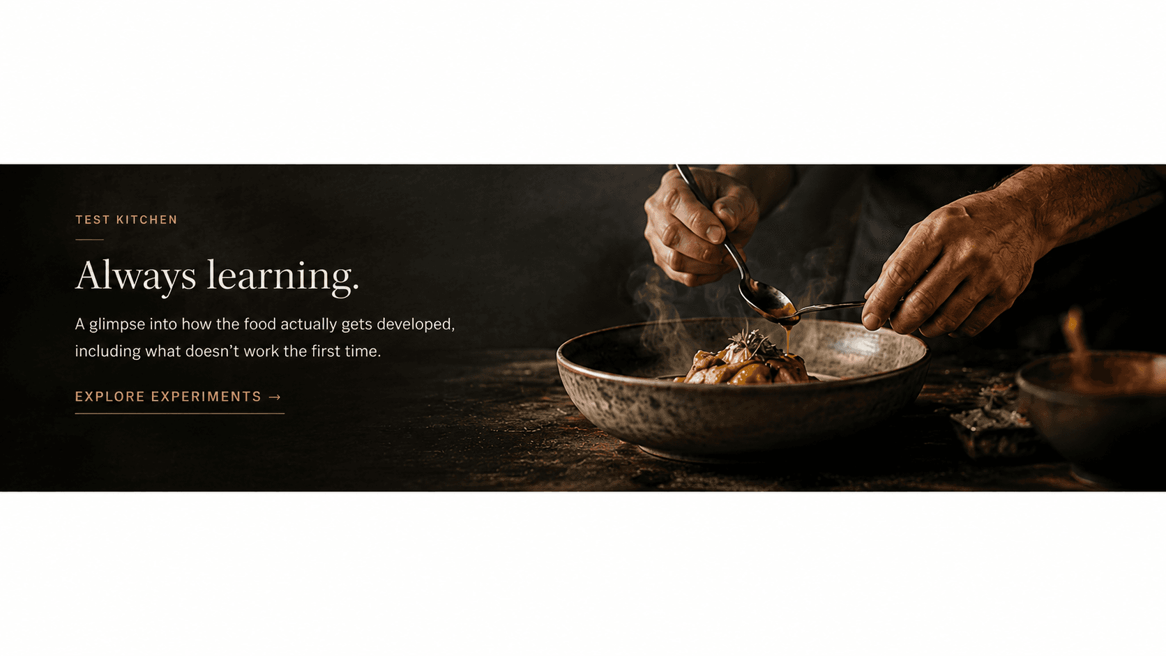 Chef's hands finishing a plated dish with a spoon of sauce, steam rising, in the Test Kitchen