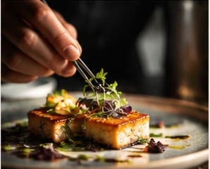 Tweezers placing microherbs on a plated dish