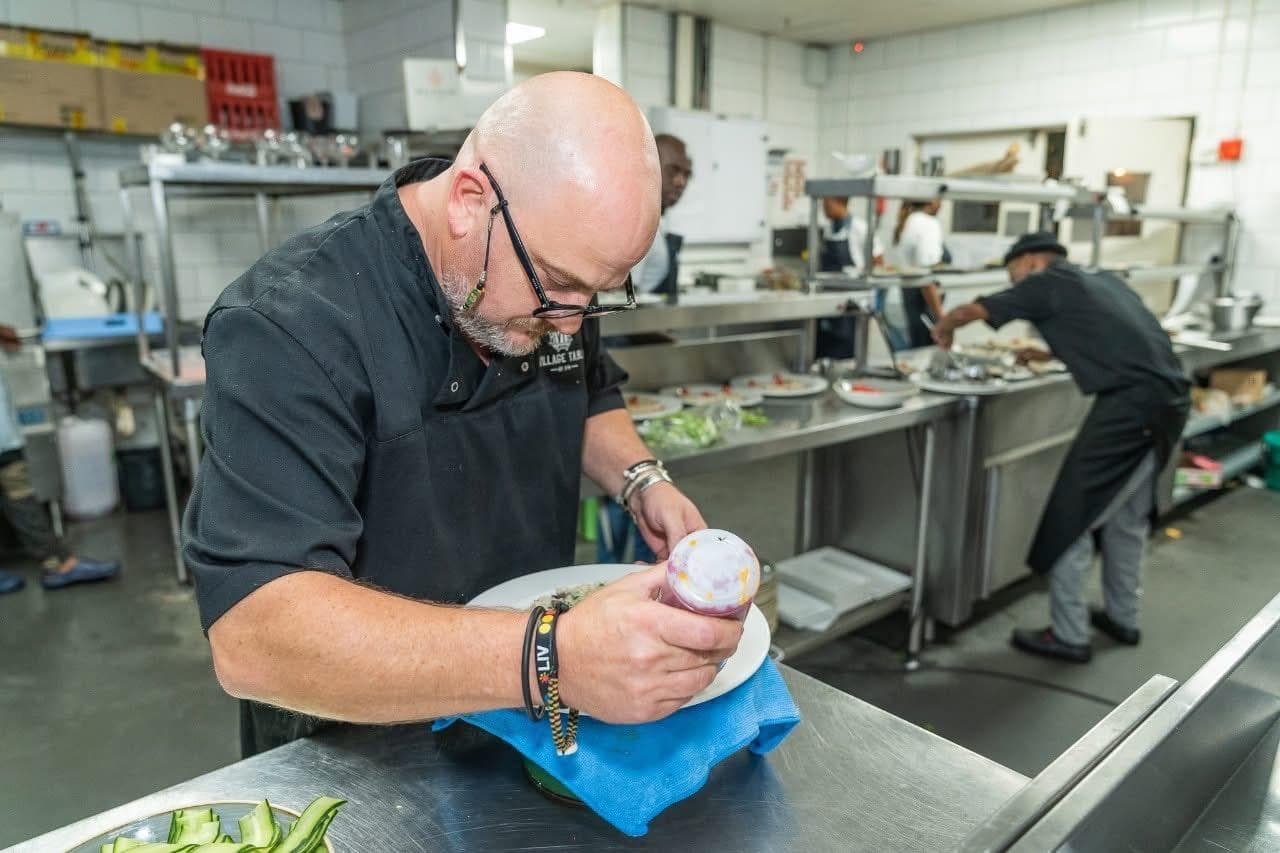 Paul at the pass, wiping the rim of a plate before it goes out